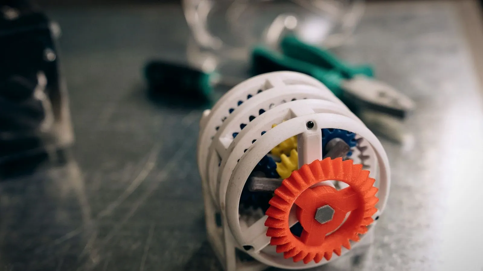 3D printed plastic gear mechanism resting on a metal workbench