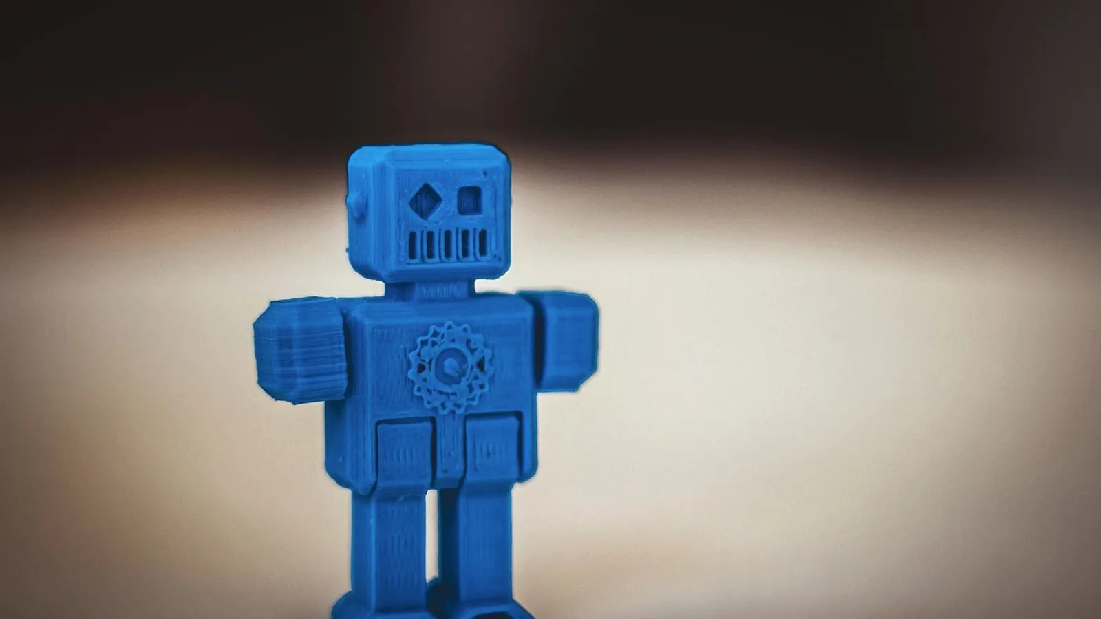 Blue 3D printed toy robot standing on a table, with visible layer lines