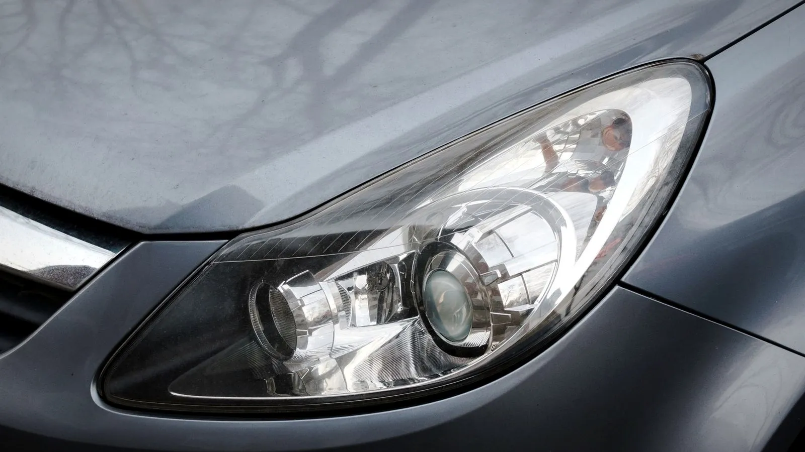 Clear plastic headlight cover on a gray car, close up