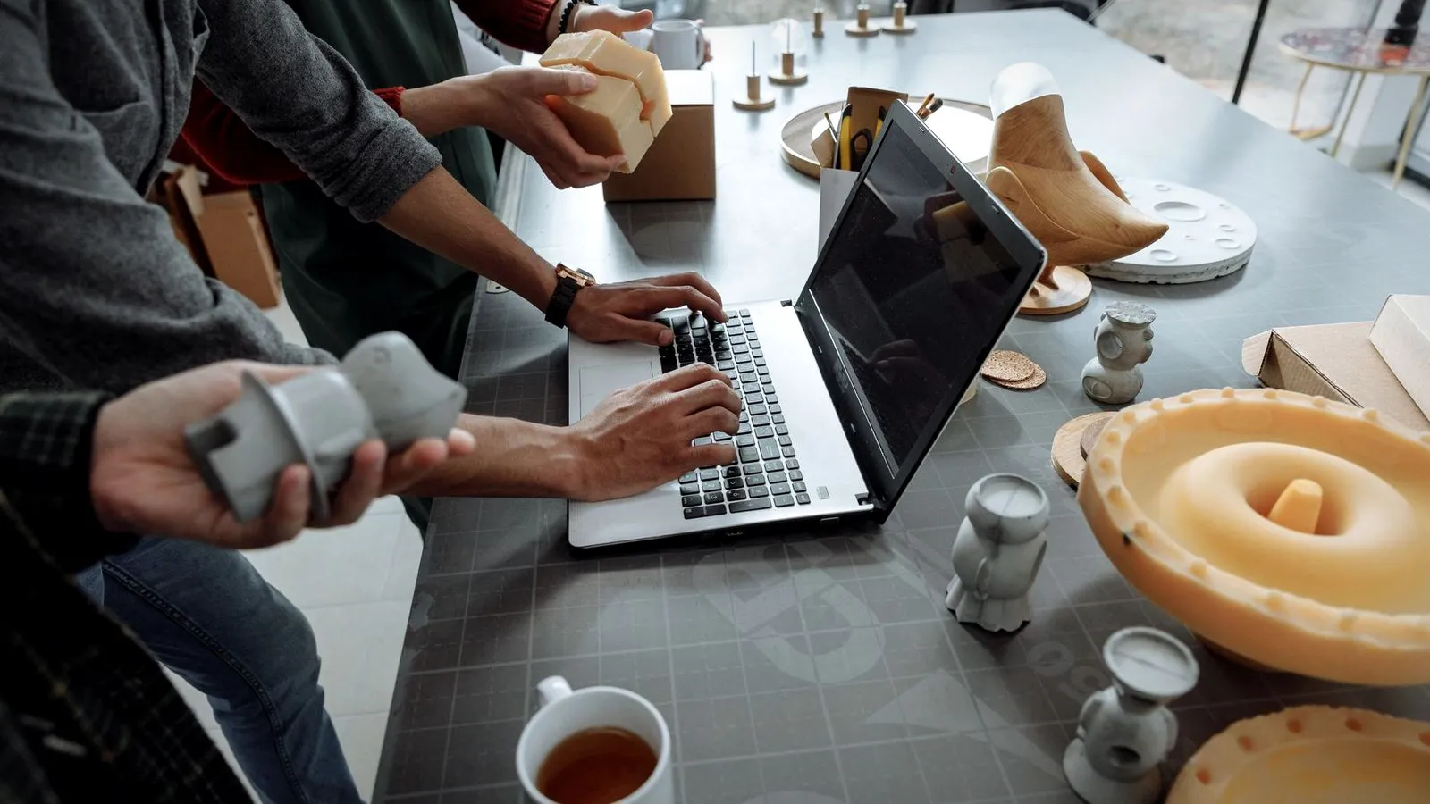 People at a table with a laptop comparing 3D printed prototype parts