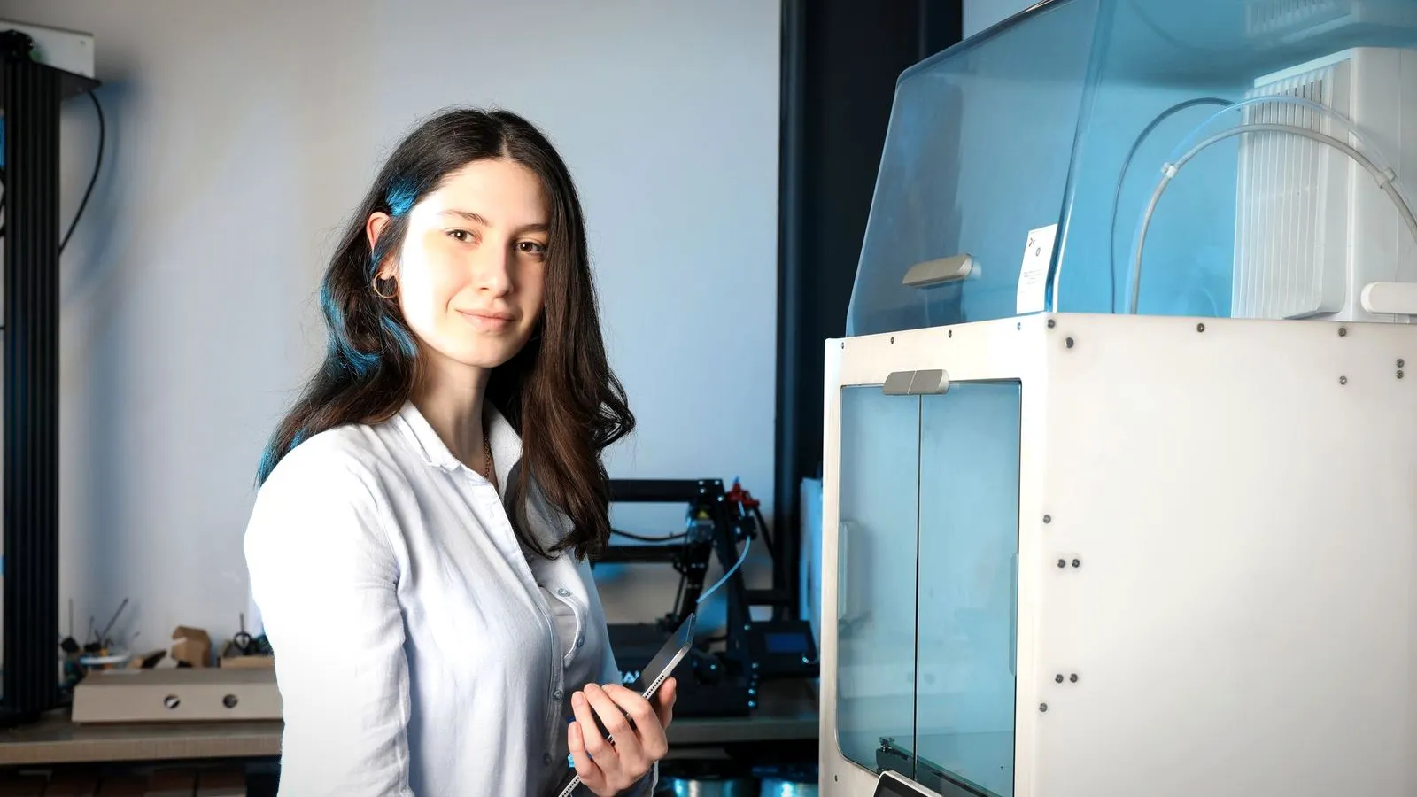 Engineer holding a tablet beside a large enclosed 3D printer