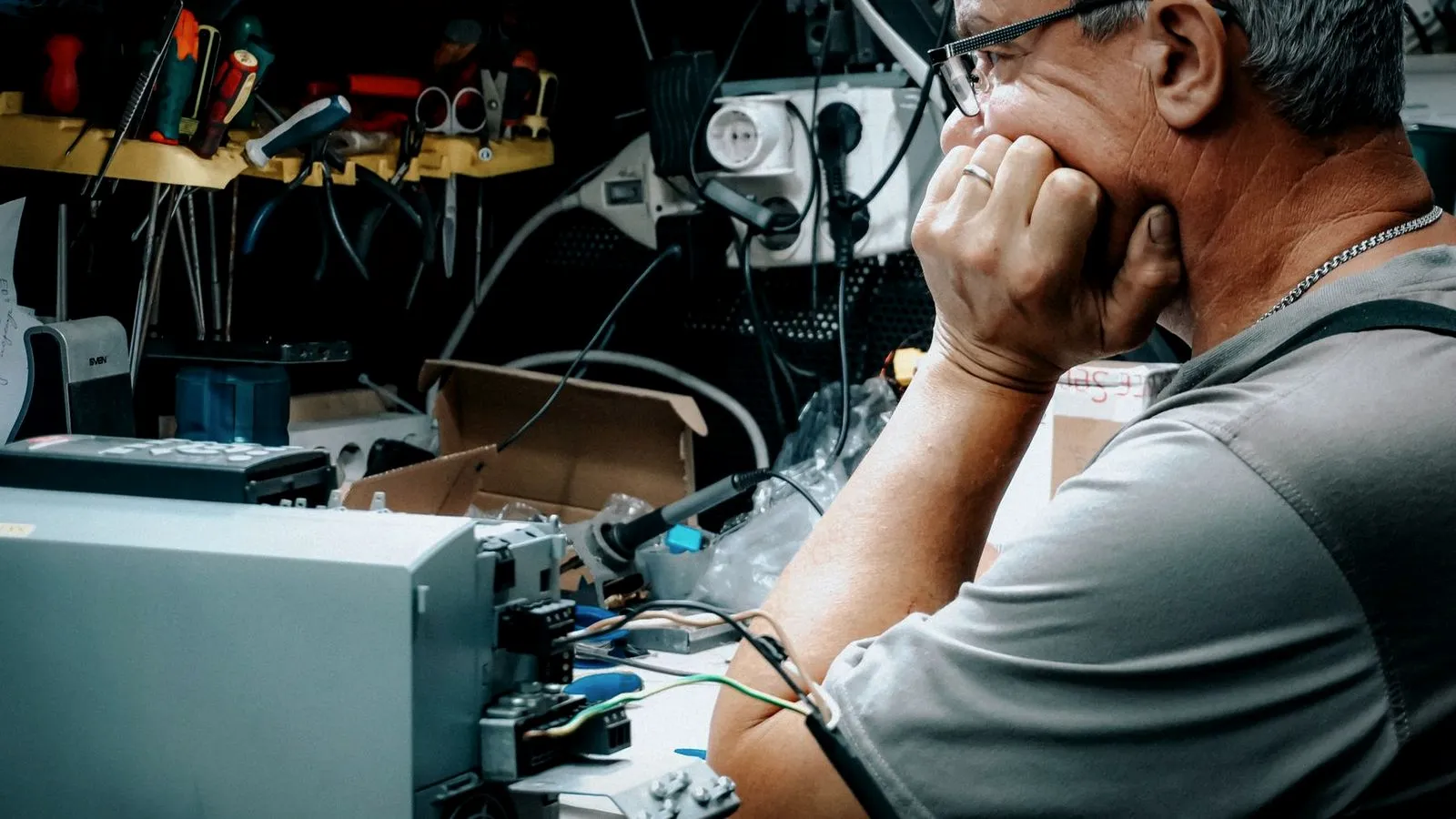 Man studying electronic equipment on a cluttered workbench