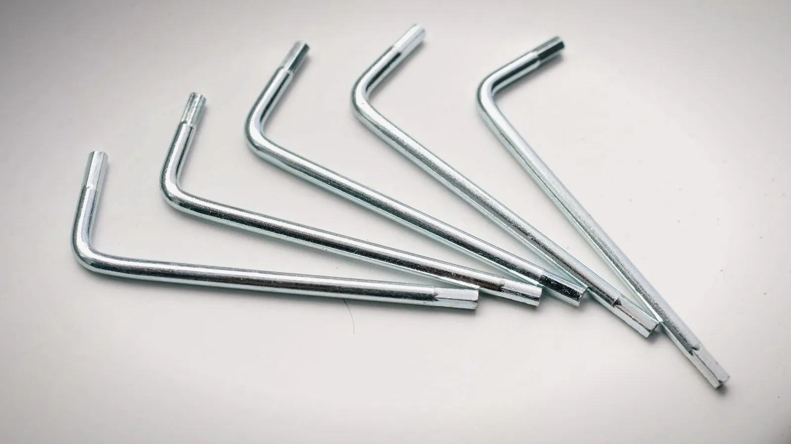 Five metal hex keys fanned out on a white surface